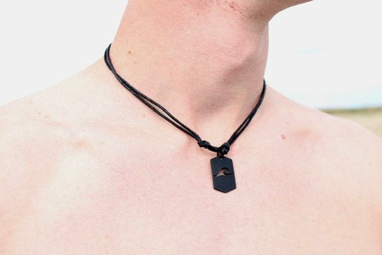 Black dog tag necklace with cut-out wave pendant detail view