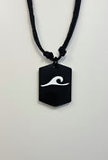 Black pendant with white wave design on a black cord against a white background